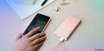 Telefonul mobil de pe un birou fiind încărcat cu mâna unei femei care ajunge la telefon pentru a se conecta la aplicația lor de mobile banking