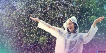 Mujer con bata blanca, bailando bajo la lluvia porque ha creado un fondo para días de lluvia para lograr el bienestar financiero